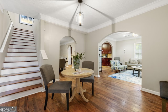 dining room with dark wood-type flooring, a textured ceiling, and crown molding