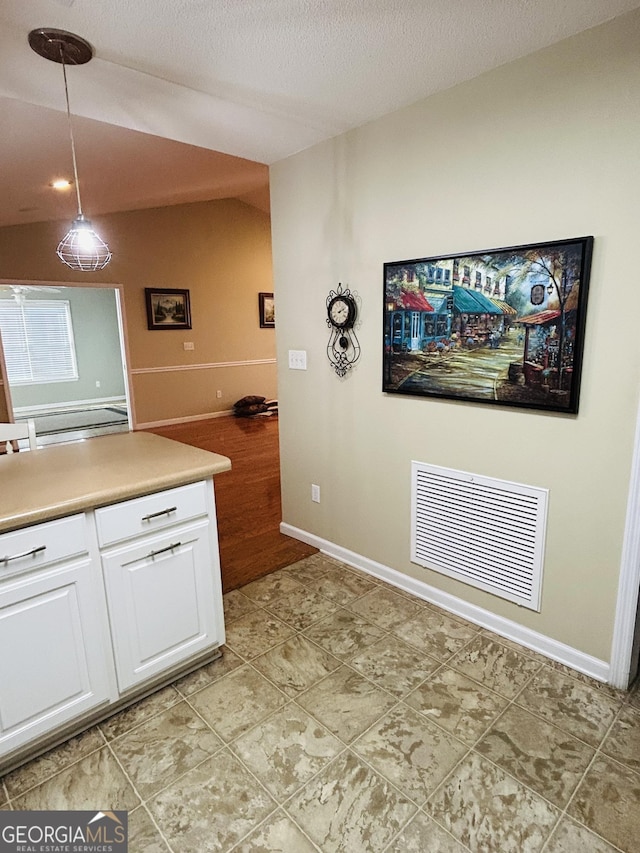 kitchen with decorative light fixtures, white cabinetry, and a textured ceiling