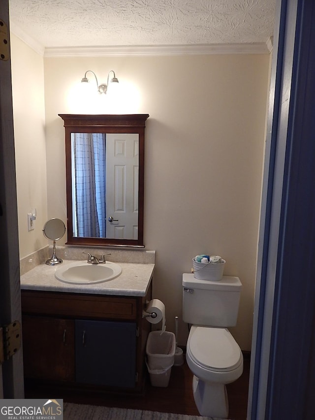 bathroom featuring a textured ceiling, toilet, vanity, and ornamental molding