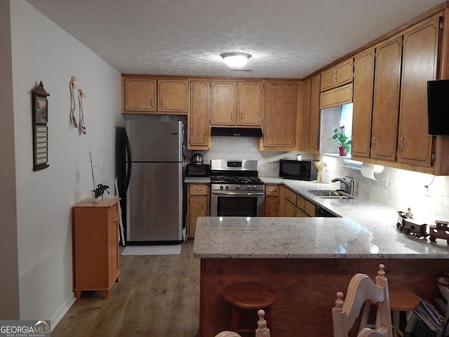 kitchen featuring stainless steel appliances, decorative backsplash, sink, dark hardwood / wood-style floors, and kitchen peninsula