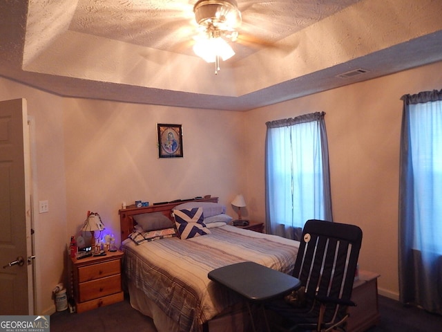 bedroom with ceiling fan and a raised ceiling