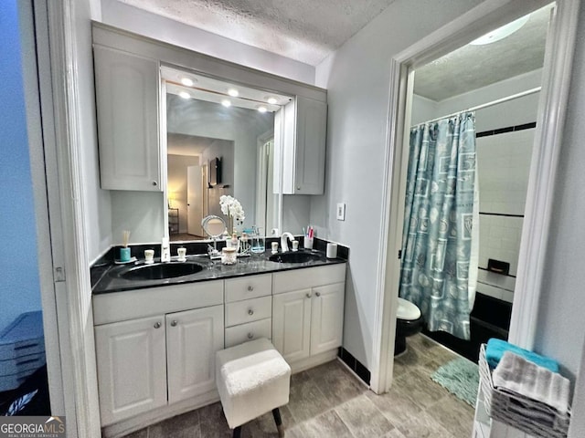 bathroom featuring toilet, a textured ceiling, and vanity