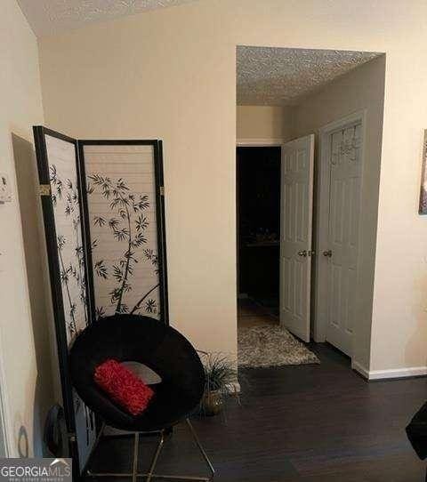 corridor with a textured ceiling and dark hardwood / wood-style floors