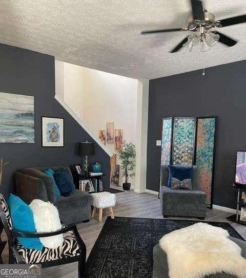 living room featuring hardwood / wood-style flooring, a textured ceiling, and ceiling fan