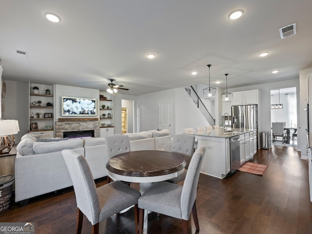 dining space with dark hardwood / wood-style flooring, a fireplace, built in features, and ceiling fan