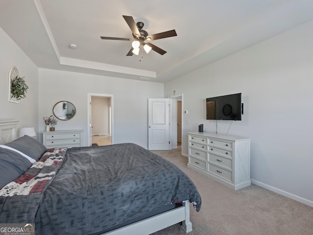 carpeted bedroom with ceiling fan and a tray ceiling