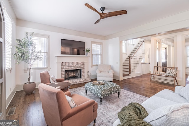 living room featuring a brick fireplace, hardwood / wood-style flooring, and ceiling fan