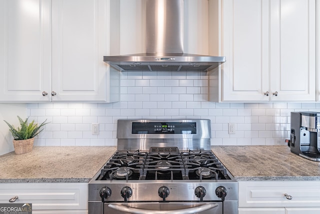 kitchen with gas range, white cabinetry, tasteful backsplash, and wall chimney range hood