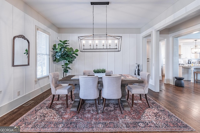 dining room featuring dark wood-type flooring and an inviting chandelier