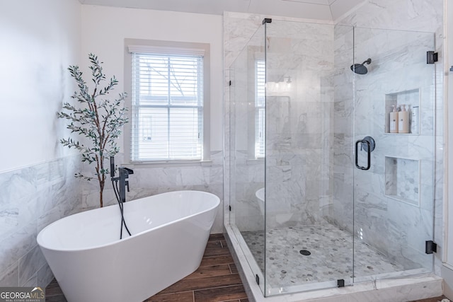 bathroom featuring independent shower and bath, hardwood / wood-style floors, and tile walls