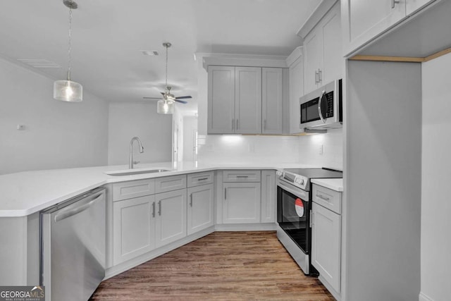 kitchen with appliances with stainless steel finishes, tasteful backsplash, sink, kitchen peninsula, and pendant lighting