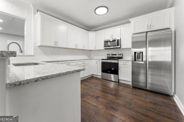 kitchen with light stone countertops, appliances with stainless steel finishes, white cabinetry, decorative backsplash, and sink