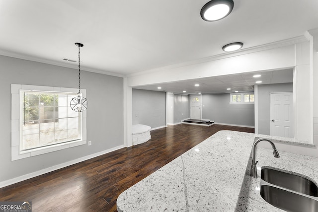 kitchen with light stone counters, sink, hanging light fixtures, and plenty of natural light