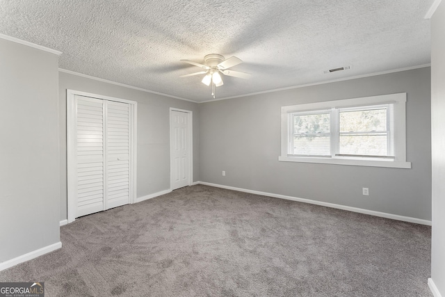 unfurnished bedroom with multiple closets, carpet flooring, crown molding, a textured ceiling, and ceiling fan