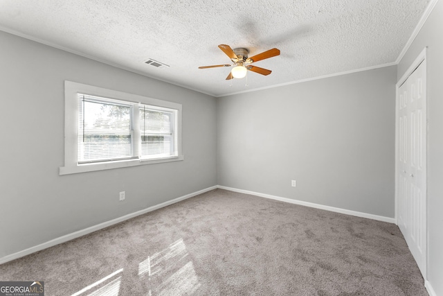 carpeted empty room with a textured ceiling, ceiling fan, and ornamental molding