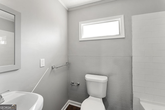 full bathroom with tile walls, sink, toilet, a textured ceiling, and ornamental molding