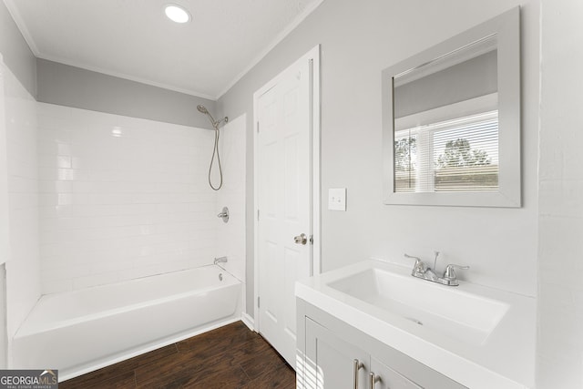 bathroom with wood-type flooring, tiled shower / bath, vanity, and ornamental molding