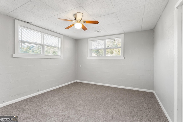 empty room with ceiling fan, a paneled ceiling, and carpet floors