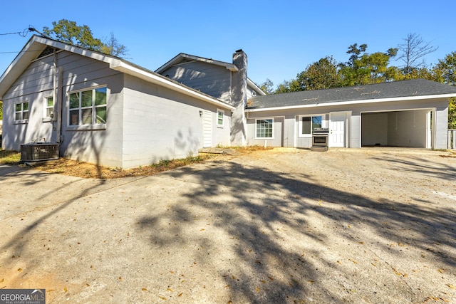 back of property featuring a garage and central AC unit