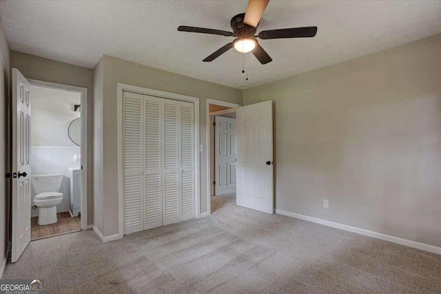 unfurnished bedroom with light carpet, ceiling fan, a closet, and ensuite bath