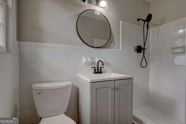 bathroom featuring vanity, a tile shower, tile walls, and toilet