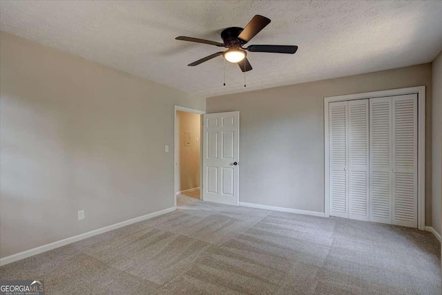 unfurnished bedroom with ceiling fan, light colored carpet, a textured ceiling, and a closet