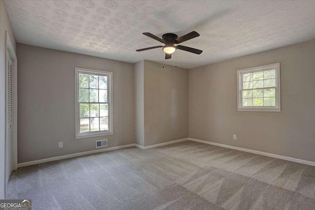 unfurnished room featuring light carpet, ceiling fan, and a textured ceiling