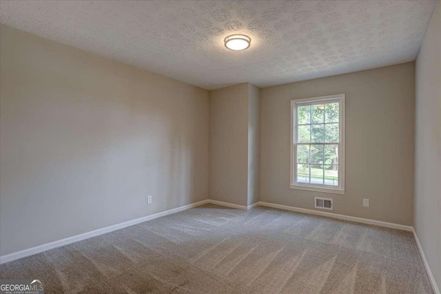 spare room with light carpet and a textured ceiling