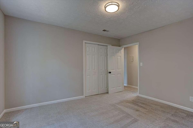 unfurnished bedroom with light carpet, a closet, and a textured ceiling