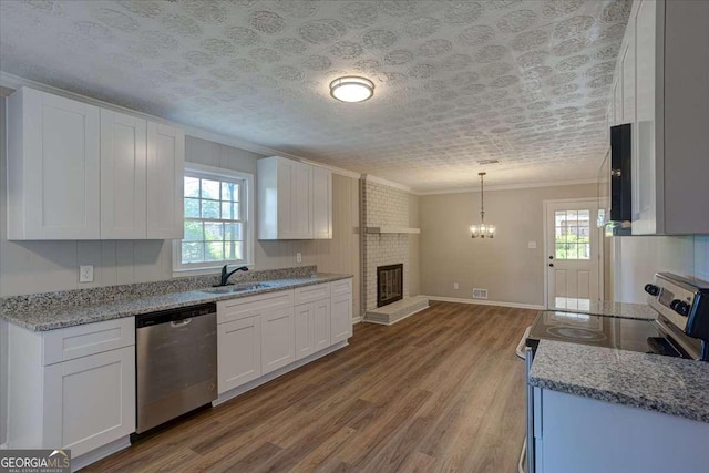 kitchen featuring appliances with stainless steel finishes, decorative light fixtures, sink, white cabinets, and crown molding