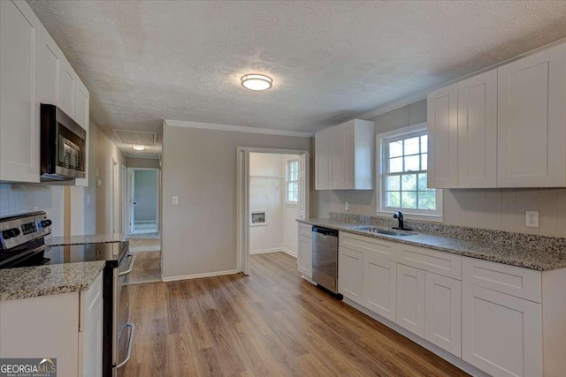 kitchen with sink, light wood-type flooring, stainless steel appliances, and white cabinetry