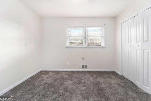 unfurnished bedroom featuring a closet and dark colored carpet