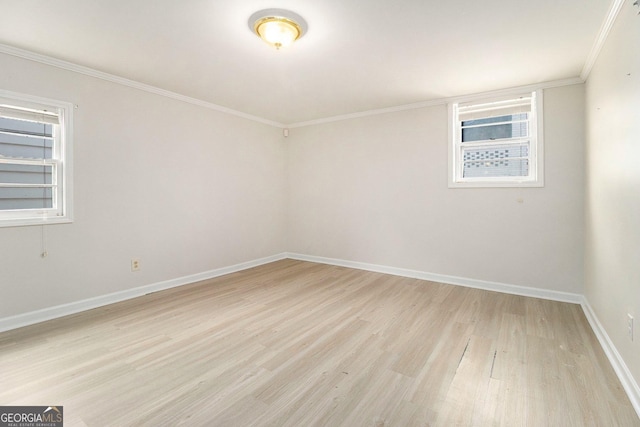 spare room with ornamental molding, a wealth of natural light, and light hardwood / wood-style floors