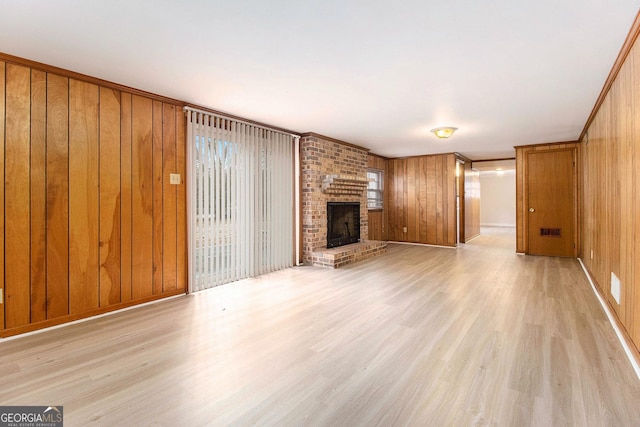 unfurnished living room with wooden walls, a fireplace, and light hardwood / wood-style floors