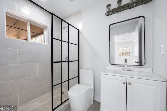 bathroom with vanity, toilet, and a tile shower