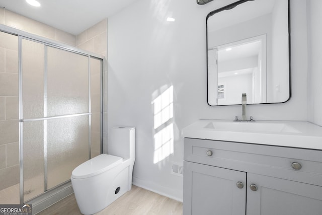 bathroom featuring an enclosed shower, vanity, wood-type flooring, and toilet