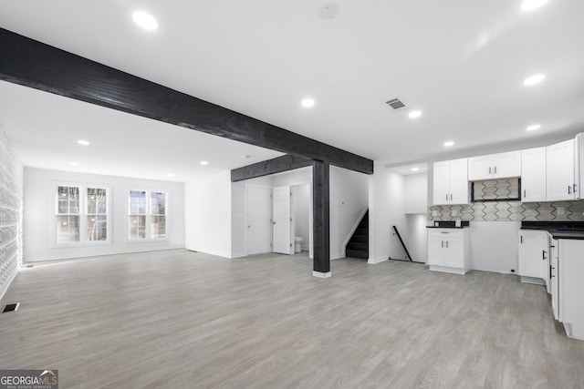 kitchen with decorative backsplash, white cabinets, beam ceiling, and light hardwood / wood-style flooring