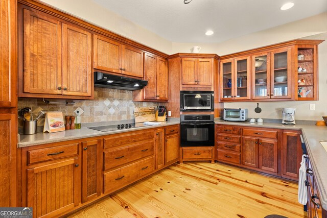 kitchen with backsplash, black appliances, and light hardwood / wood-style flooring