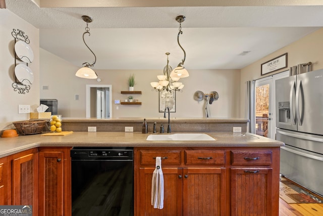 kitchen featuring sink, hanging light fixtures, stainless steel fridge, and a textured ceiling