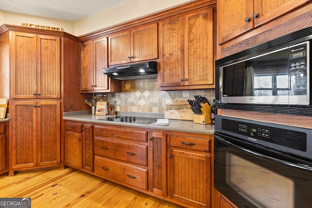 kitchen with black appliances, tasteful backsplash, and light wood-type flooring