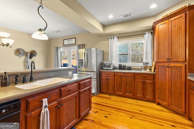 kitchen with stainless steel refrigerator with ice dispenser, sink, a healthy amount of sunlight, and light wood-type flooring