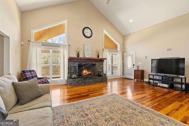 living room with a wealth of natural light, hardwood / wood-style floors, and high vaulted ceiling