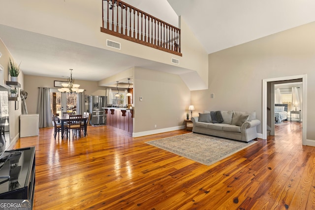 living room with hardwood / wood-style floors, an inviting chandelier, and a towering ceiling