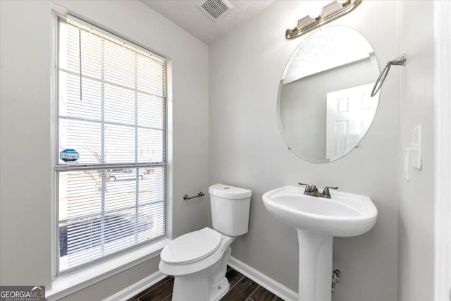 bathroom with plenty of natural light, a textured ceiling, and toilet