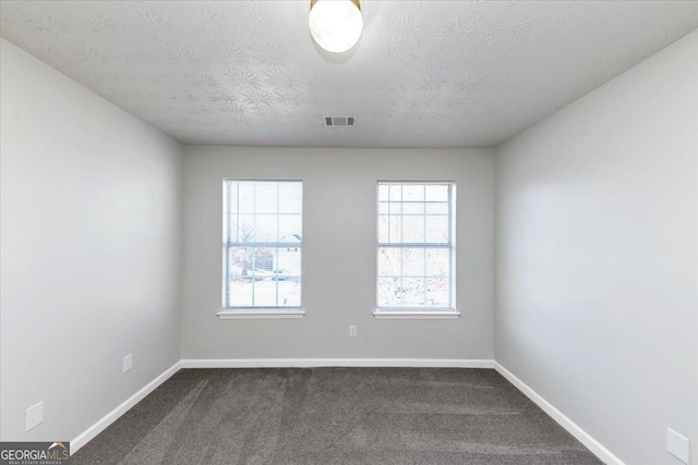 unfurnished room with dark carpet and a textured ceiling