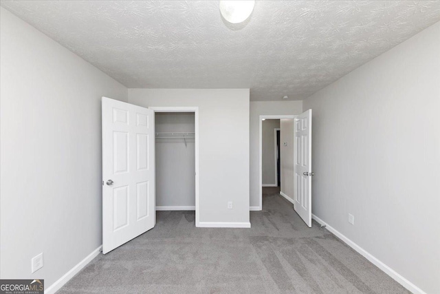 unfurnished bedroom featuring light carpet, a textured ceiling, and a closet