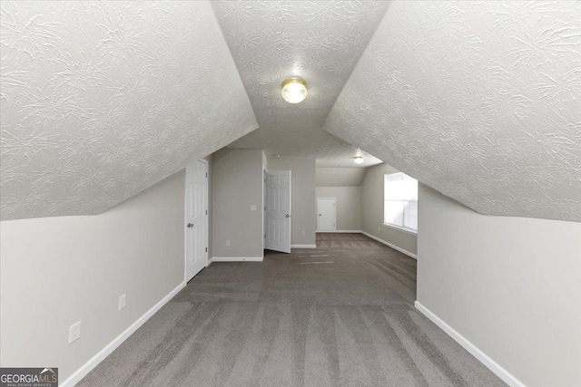 additional living space with vaulted ceiling, a textured ceiling, and carpet floors