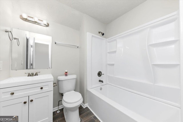 full bathroom featuring a textured ceiling, washtub / shower combination, vanity, and toilet