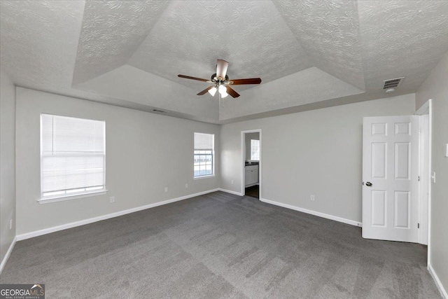 carpeted empty room featuring ceiling fan, a textured ceiling, and a raised ceiling