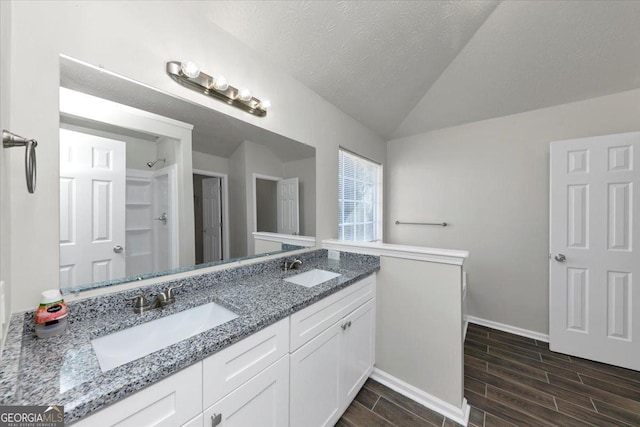 bathroom featuring a textured ceiling, vaulted ceiling, and vanity